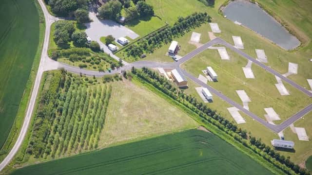 Aerial view of Newton Shores Hotel, surrounded by green fields, a pond, and neatly arranged accommodations.