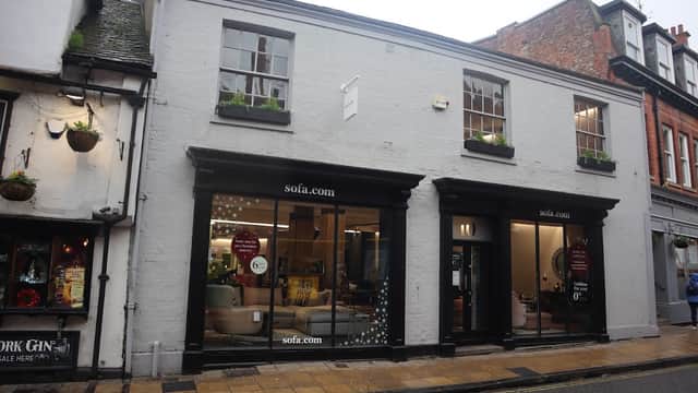 Two-story furniture shop with large windows displaying sofas, located on a cobbled street in York, Yorkshire.