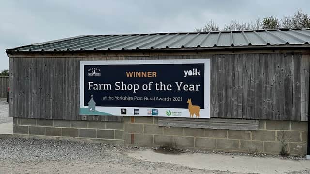 Wooden building with a metal roof, featuring a large sign announcing "Winner Farm Shop of the Year" in Minskip.