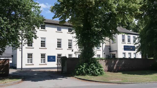 White building with large windows, surrounded by trees and a grassy area, located on a street in North Ferriby.