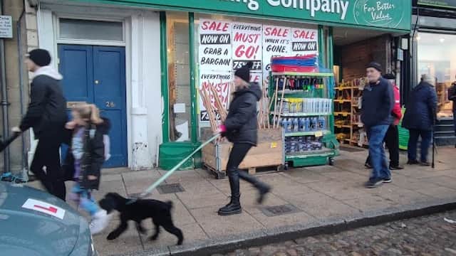 Shopfront of Yorkshire Trading Company in Richmond, with sale signs and people walking by, including a dog.