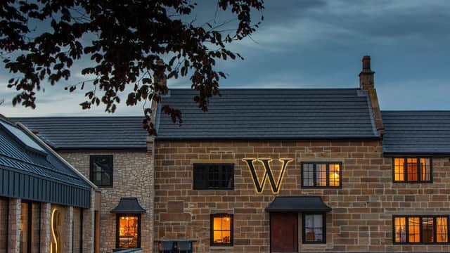 Wainstones Hotel features a stone facade with illuminated letters, warm windows, and a cloudy evening sky.