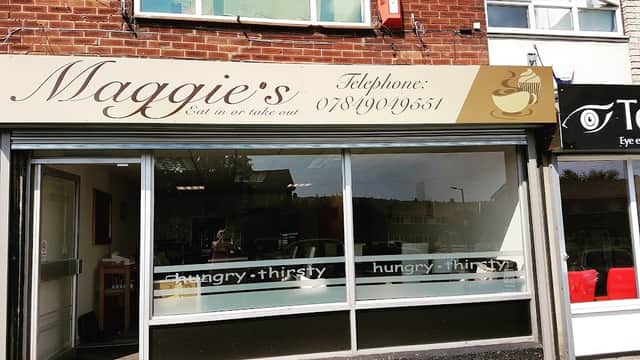 Maggie's Grocers storefront with large windows, signage, and a nearby shop featuring red chairs.