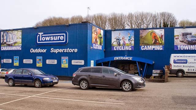 Blue building with large signs for cycling, camping, and towing; parked cars in front and entrance visible.