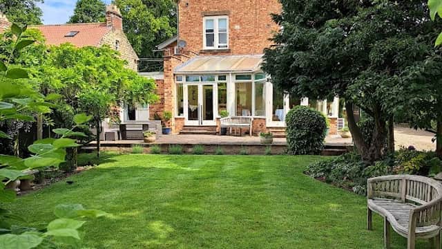 Victorian-style hotel with a conservatory, surrounded by a lush garden and greenery in Pickering, Yorkshire.