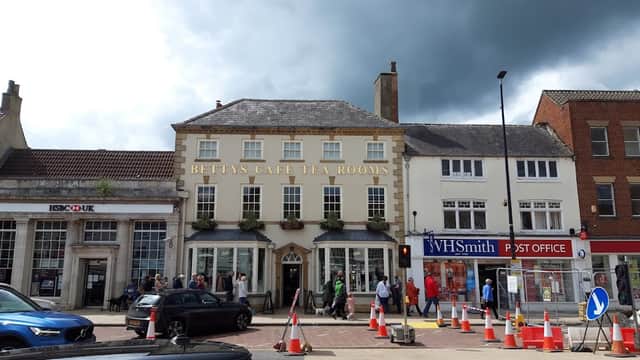 Betty's Café Tea Rooms with pedestrians, cars, and construction cones outside in Northallerton, Yorkshire.