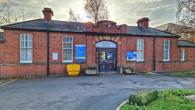 Seacroft Hospital's brick facade features a central entrance, signage, and surrounding greenery under a cloudy sky.