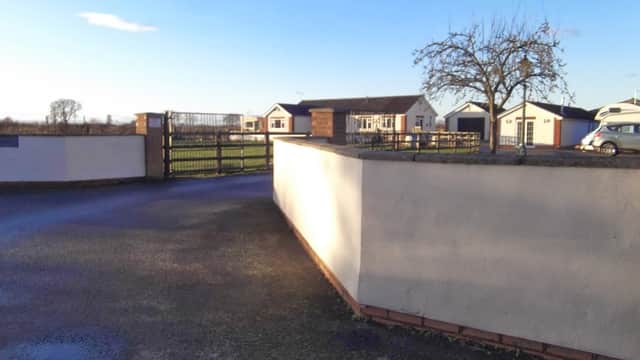 Entrance gate to The Ranch Caravan Site, with a view of holiday homes and green fields in the background.