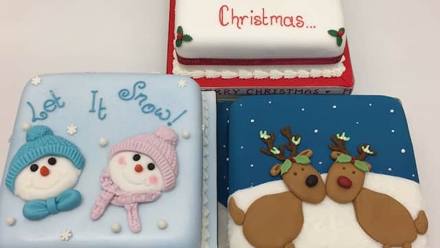 Three festive cakes: one with snowmen, one with a Santa and snowman, and another with reindeer, all decorated for Christmas.