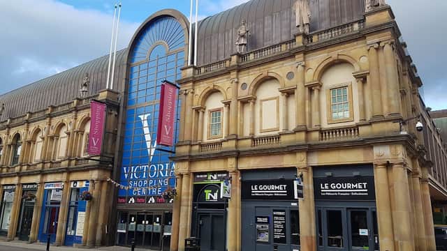 Historic architecture of Victoria Shopping Centre featuring large blue entrance and storefronts with signage.