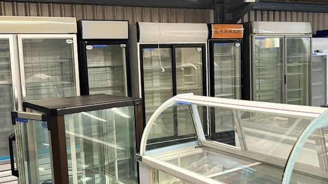 Display of various refrigeration units, including glass-fronted freezers and ice cream cabinets, in a warehouse setting.