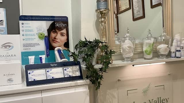 Reception area of Holme Valley Skin Clinic with a mirror, skincare products, and framed certificates on the wall.