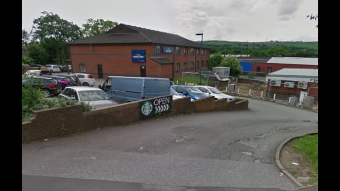 Pay & Display parking area with cars, a Starbucks sign, and a building in the background in Norristhorpe, Yorkshire.