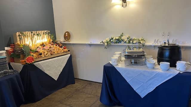 Buffet setup with decorative food display, silver serving trays, and white tablecloths in a cozy bar setting.
