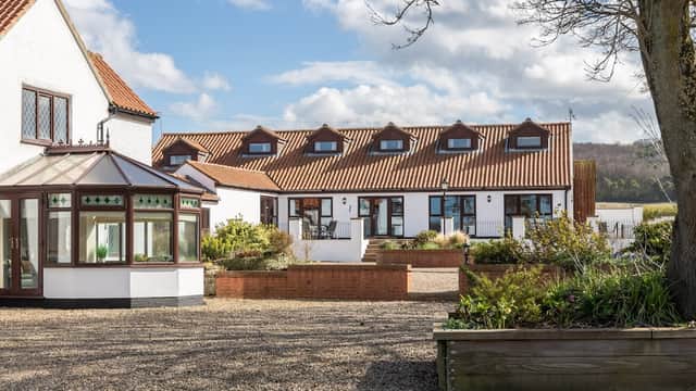 Charming hotel with a red-tiled roof, landscaped gardens, and a glass conservatory under a blue sky in West Knapton.