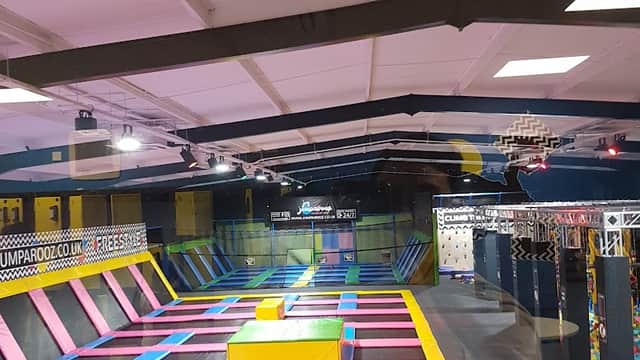 Colorful trampolines with various shapes and a climbing wall in a spacious indoor park.