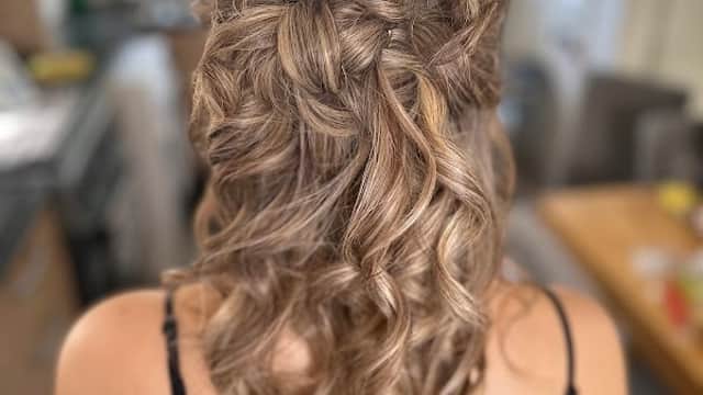 Long, wavy hair styled with elegant curls and decorative clips, seen from the back in a bright, modern interior.