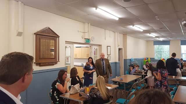 Interior of St Johns Community Centre with tables, chairs, and people mingling during an event.