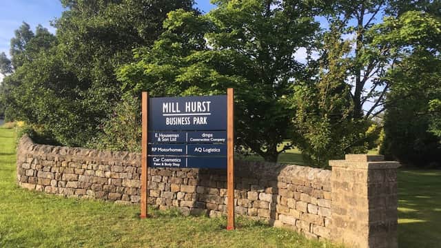 Sign for Mill Hurst Business Park surrounded by greenery and a stone wall in Dacre, North Yorkshire.