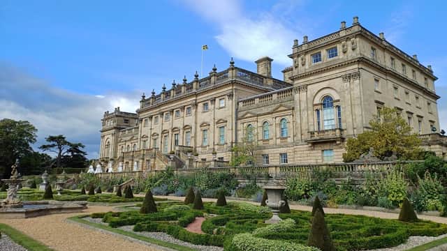 Harewood House with intricate gardens, manicured hedges, and a blue sky in the background.