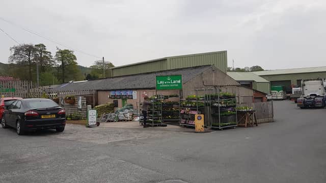 Garden centre with a café, featuring a gravel parking area, plant displays, and green signage in Settle, Yorkshire.