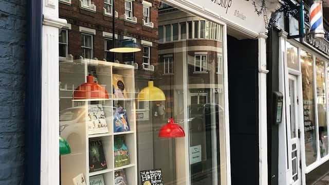 Charming bookshop window displays colorful lamps, books, and festive decorations in a quaint York street.