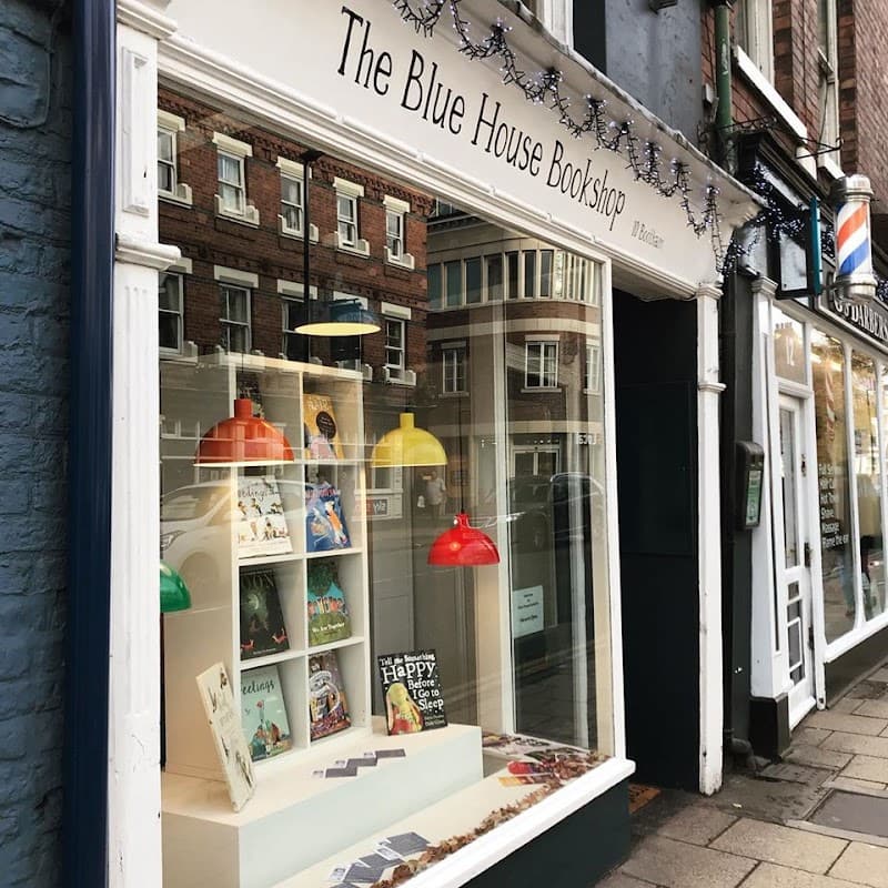 Charming bookshop window displays colorful lamps, books, and festive decorations in a quaint York street.