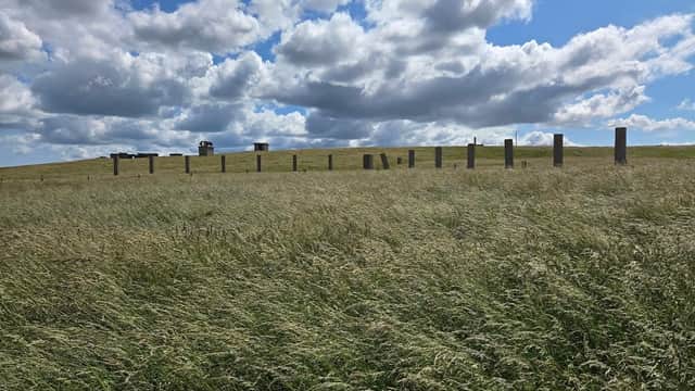 Stone pillars on grassy hill under a cloudy sky at Former RAF Bempton, Yorkshire.