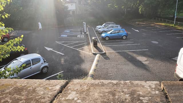 Bell Lane Car Park with 36 spaces, featuring several parked cars and green trees in the background.