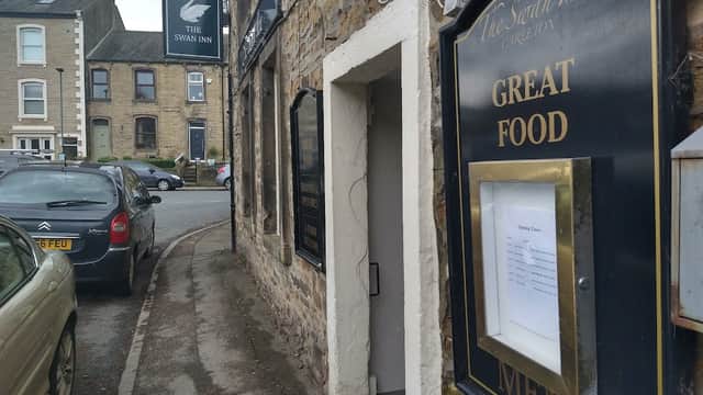 The Swan Inn sign, stone exterior, menu display, and parked cars along a quiet street in Carleton-in-Craven.