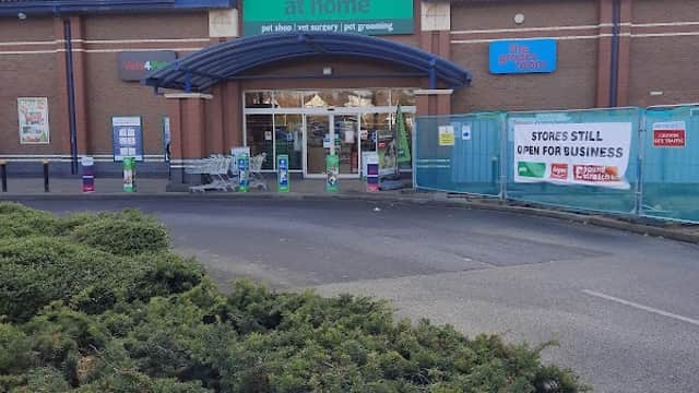 Front entrance of Pets at Home store with signage, surrounded by greenery and construction barriers.