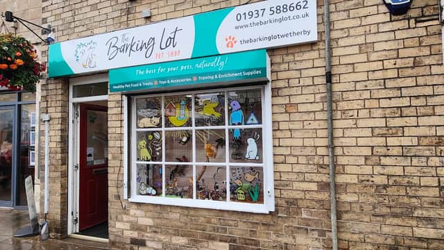 Colorful shopfront featuring "The Barking Lot" sign, pet-themed window display, and a welcoming entrance.