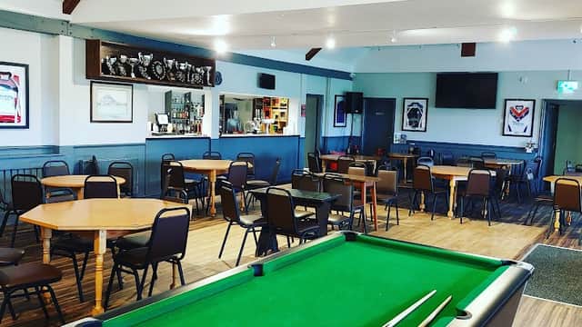 Interior of New Earswick Sports & Social Club featuring a pool table, tables, chairs, and trophies on display.