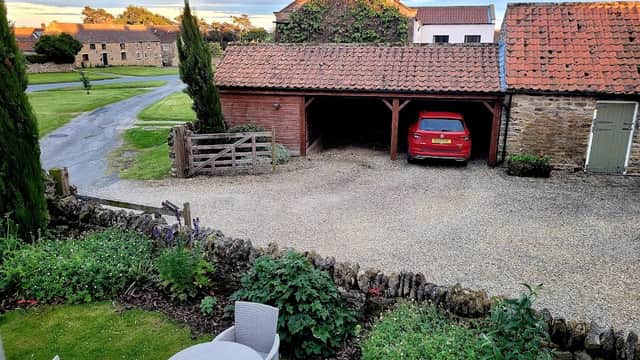 Pond Farm Bed & Breakfast features a gravel driveway, a red car, and outdoor seating among lush greenery.