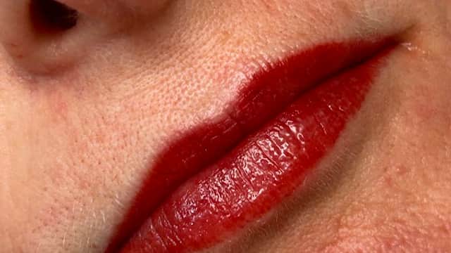 Close-up of lips with deep red lipstick, showcasing smooth skin and subtle texture.