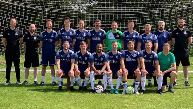 South Milford Football Club team poses in blue jerseys on a grassy field with a goal net in the background.
