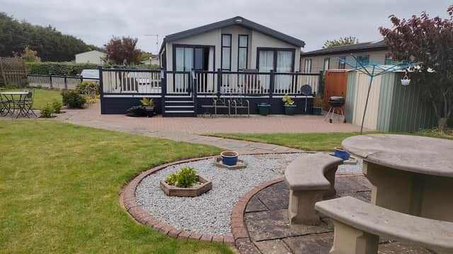Holiday park with a modern cabin, landscaped garden, stone seating area, and gravel pathways in Skipsea, Yorkshire.