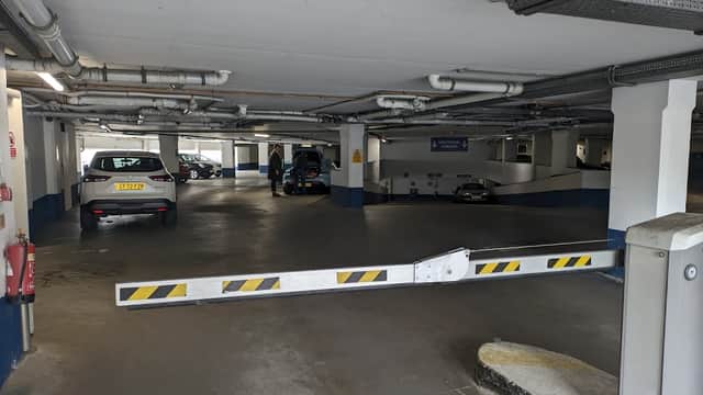 Pay & Display car park with parked cars, a barrier, and visible signage in a multi-level structure.