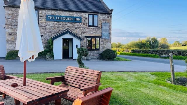 The Chequers Inn features a stone exterior, outdoor seating, and a green landscape in Bishop Thornton, Yorkshire.