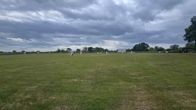 Cricket match in progress on a green field under a cloudy sky at Kelfield Cricket Club, North Yorkshire.