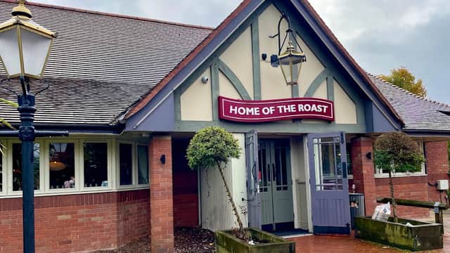 Quaint cafe entrance with "HOME OF THE ROAST" sign, lanterns, and landscaped greenery in Edenthorpe, Yorkshire.