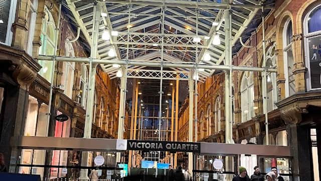 Victoria Quarter in Leeds, featuring a glass roof, modern architecture, and people walking through the shopping arcade.