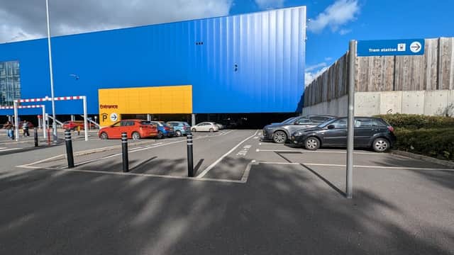 Ikea Sheffield Park and Ride with blue building, yellow entrance, parked cars, and sign for tram station.