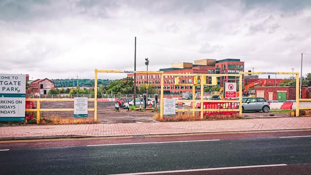 Welcome sign for Westgate Car Park with barriers, parking spaces, and buildings in the background on a cloudy day.