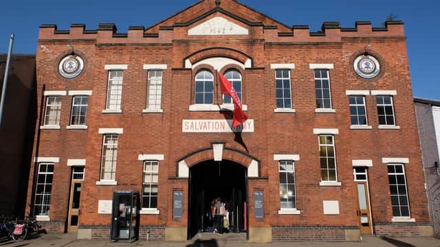 Historic brick building with arched windows, a flag, and signage for the Salvation Army in York. Clear blue sky above.