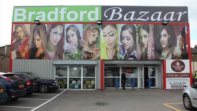 Colorful storefront featuring diverse models in traditional attire, showcasing the name "Bradford Bazaar" prominently above.