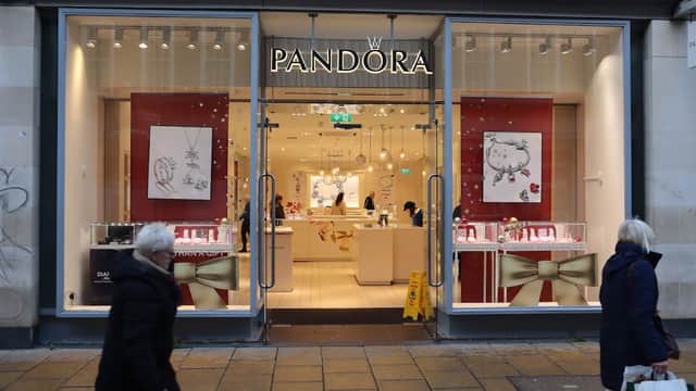 Jewellery store with large glass windows, featuring displays of necklaces and charms, and a festive red and gold theme.