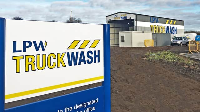 Sign for LPW Truckwash outside a modern service station building in Leeming Bar, Yorkshire, with cloudy skies above.