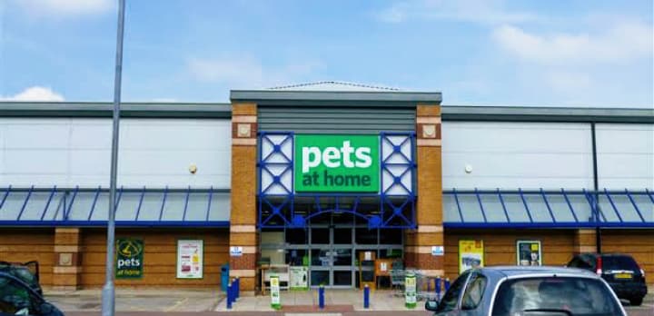 Pets at Home store entrance with blue accents and signage, surrounded by a parking lot and clear sky.