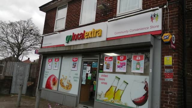 Community convenience store with colorful signage, displaying drinks and snacks, and a pink child's bike outside.